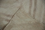 Close-up of distressed Tulu rug's textured pile in ivory tones, revealing flat weave reverse and intact selvage.