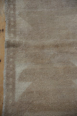 Distressed vintage Tulu rug's worn pile, showing primitive beige and ivory pattern, side selvage.