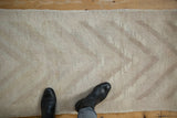 Textured vintage distressed Tulu rug showing subtle ivory and mauve arrowed pattern.