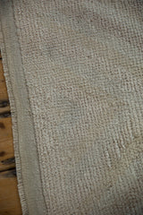 Distressed ivory loop pile texture with intact side cord selvage.