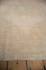 Distressed vintage Oushak rug with low cream pile and subtle faded sea foam pattern.