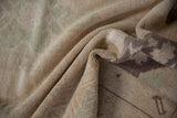 Detail of the vintage Oushak rug pile showing distressed cream and faded sea foam abrash.