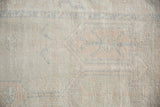 Vintage distressed Oushak rug pile with pale peach, ivory, and visible foundation.