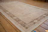 Angled view of a vintage Oushak carpet highlighting its soft, worn texture and coffee brown border.