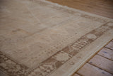 Angled view of the distressed Oushak's even wear, showing its textural low pile and brown border.