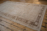 Angled view of a distressed Turkish Oushak carpet highlighting its evenly worn, low pile texture.