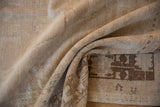 The hand-knotted back and softly worn, sandy-toned pile of a vintage distressed Oushak rug.