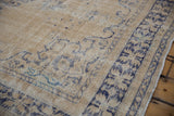 Vintage distressed Oushak rug with worn cream pile and navy serrated floral border.