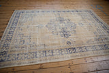 Vintage distressed Oushak rug corner, blue serrated floral border, faded cream field.