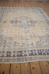 Vintage Distressed Oushak carpet's serrated navy floral border on a worn cream field.