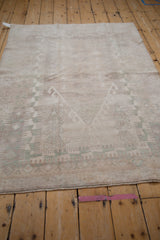 Distressed Oushak rug pile revealing faded geometric motifs in silver, ivory, and seafoam.