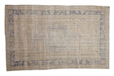 Vintage distressed Oushak carpet with a faded blue medallion design on a neutral ivory and beige ground.