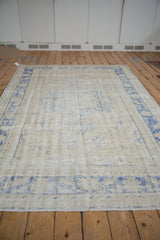 Perspective view of a vintage distressed Oushak carpet highlighting its decorative, faded pattern.
