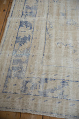 Textured wear across the knot heads of a distressed Oushak carpet in shades of ivory and blue.