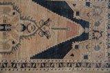 Faded navy, peach, and ivory geometric patterns with distressed texture on a vintage Oushak rug.