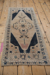 Textured faded peach, navy, and ivory geometric central medallion of a vintage Oushak rug.