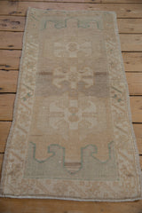 Distressed Oushak rug top end, faded floral gul, abrashed field, seafoam green vine border.