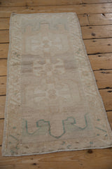 Faded triple floral guls and intact selvage on a vintage distressed Oushak rug corner.