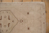 Vintage distressed Oushak rug, faded beige pile, chocolate geometric motifs, intact selvage.