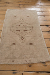 Softened beige pile, muted brown design, and intact selvage on a distressed Oushak rug.