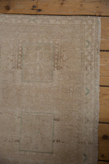 Distressed Oushak rug surface with low pile, faded beige abrash, and subtle teal motifs.