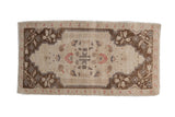 Distressed vintage Oushak rug with a floral pattern, brown corner spandrels, and red accents on an ivory field.