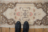 A vintage Oushak mat with even, distressed wear and floral patterns shown to scale from above.