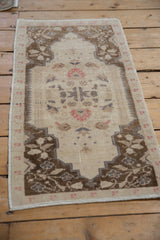 Vintage distressed Oushak rug with shield-like corner spandrels and an evenly worn low pile.