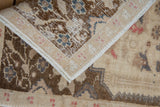 A folded corner reveals the hand-knotted construction of the vintage Oushak rug.