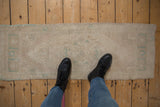 Distressed vintage Oushak runner with even, short pile, muted ivory, and faded teal patterns.