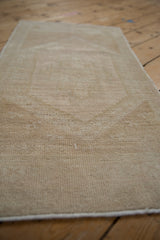 Distressed vintage Oushak rug surface showing even wear and soft antique ivory pile.