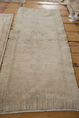 Angled view of the distressed Oushak rug, showing its worn, low-pile texture and faded neutral tones.