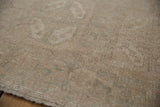 Distressed vintage Oushak rug close-up, showing even pile wear and faded floral motifs.