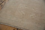 Distressed Oushak rug's pile texture, revealing even wear and muted antique ivory hues.