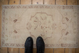 Distressed vintage Oushak rug mat with faded ivory field, worn medallion, and intricate border.