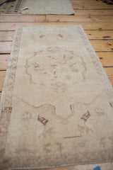 Vintage Oushak rug detail showing distressed antique ivory field and faded mauve motifs.