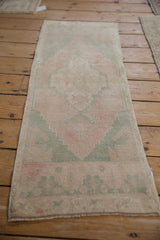 Vintage Distressed Oushak runner's faded pink, seafoam blue stepped pattern and intact side selvage.