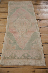 Distressed vintage Oushak runner with faded pink and seafoam geometric motifs.