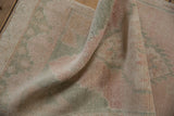 Distressed Oushak rug pile texture in faded pink, ivory, and seafoam blue.