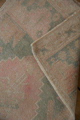 Distressed vintage Oushak pile with muted pink hues, revealing hand-knotted reverse.