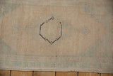 Distressed Oushak rug detail: intact selvage, faded ivory, seafoam green, navy outline.