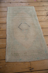 Muted ivory and seafoam green Oushak rug with distressed pile and black medallion outline.