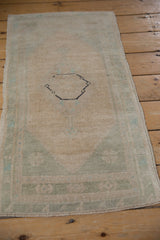 Distressed Oushak rug pile texture with antique ivory, seafoam green, and intact side selvage.