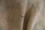 Distressed vintage Oushak rug pile showing areas of knot heads with faded ivory and green.