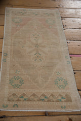 Distressed Oushak rug end with faded rose and teal geometric finials and abrashed ground.