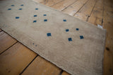 Distressed vintage Oushak rug's textured ivory pile with scattered navy blue square motifs.