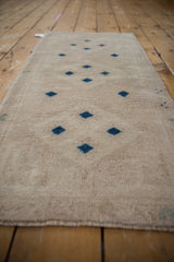 Distressed Oushak runner showing low pile texture and navy blue geometric diamond motifs.