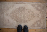 Stepped medallion design on this vintage distressed Oushak rug mat in neutral tones.