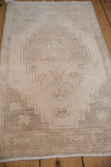 Vintage distressed Oushak mat, short ivory pile with faded stepped medallion design.
