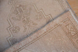 Angled view of a vintage distressed Oushak rug's faded texture and hand-knotted reverse.